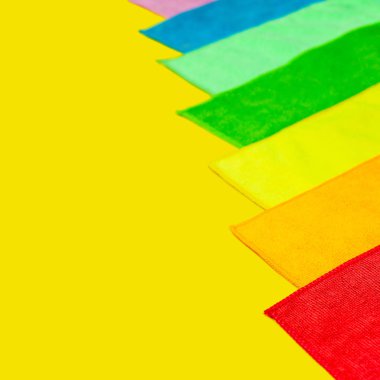 Parlak sarı bir arka plan üzerinde renkli mikrofiber toz örtüsü yalan. Ev işi ekipman kümesi.