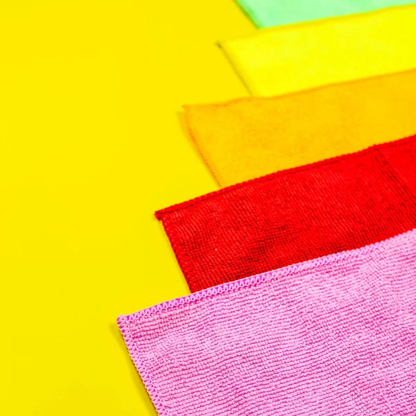 Parlak sarı bir arka plan üzerinde renkli mikrofiber toz örtüsü yalan. Ev işi ekipman kümesi.