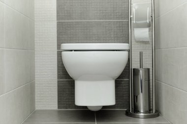 Kağıt tutucu ve tuvalet fırçası ile modern banyo beyaz klozet.