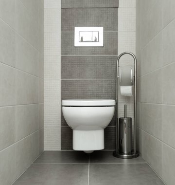 White toilet bowl in modern bathroom with paper holder and toilet brush. clipart