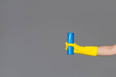 Elinde lastik eldiven mavi çöp torbası tarafsız arka plan üzerinde tutar. Bahar temizliği kavramı.