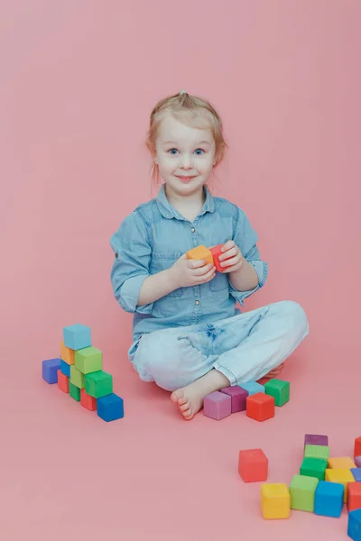 Uma Menina Encantadora Roupas Jeans Fundo Rosa Brinca Com Cubos — Fotografia de Stock
