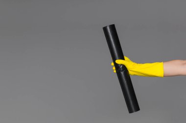 Lastik eldiven elinde çöp torbası tarafsız arka plan üzerinde geri tutar. Bahar temizliği kavramı.