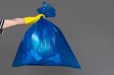 Bir mavi plastik torba çöp dolu bir lastik eldiven bir kadının elinde tutan.