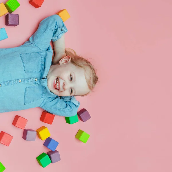 Charming Little Girl Denim Clothes Lying Pink Background Wooden Colored — Stock Photo, Image