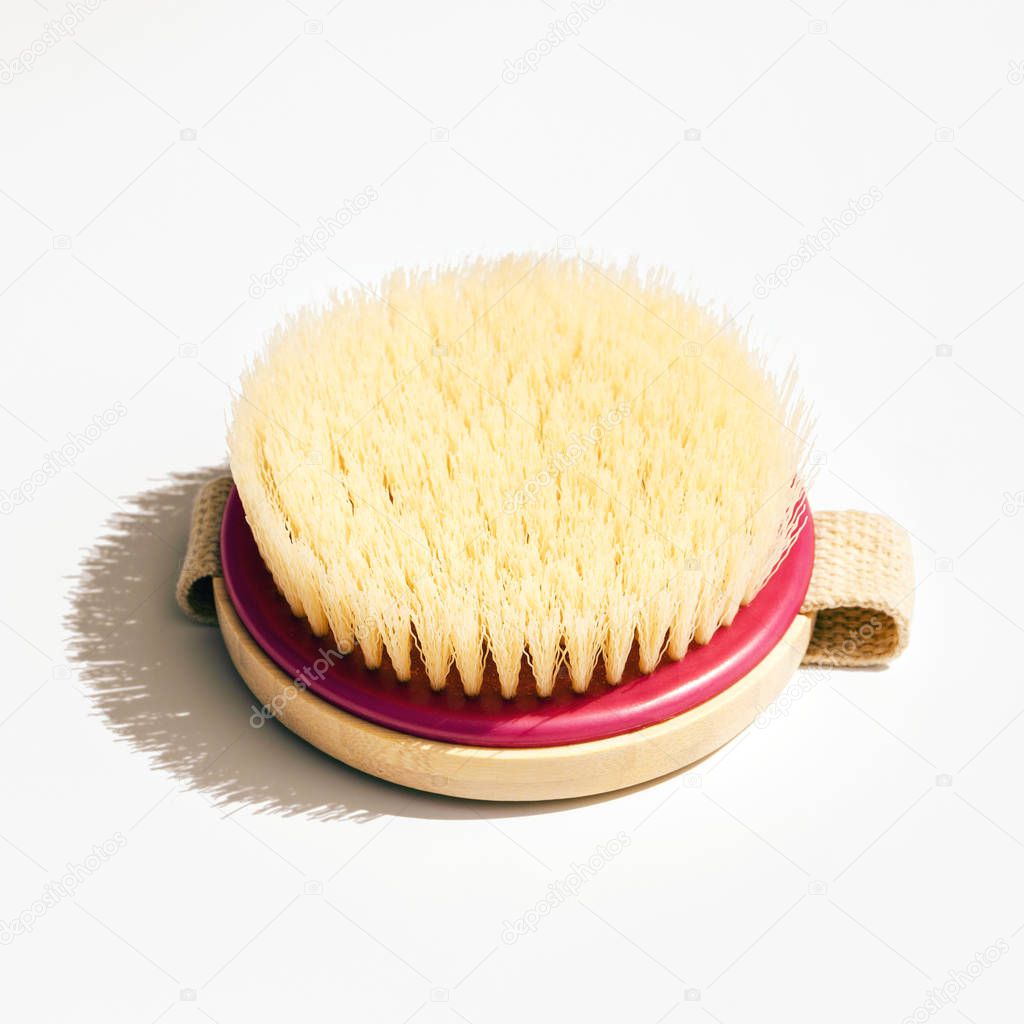 Dry body massage brush on white background at sunny day. Tool for smooth and soft skin. 