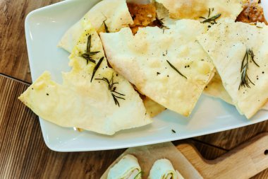 Pide ekmek meze ahşap masada beyaz bir plaka üzerinde zeytinyağı ve biberiye ile pişmiş.