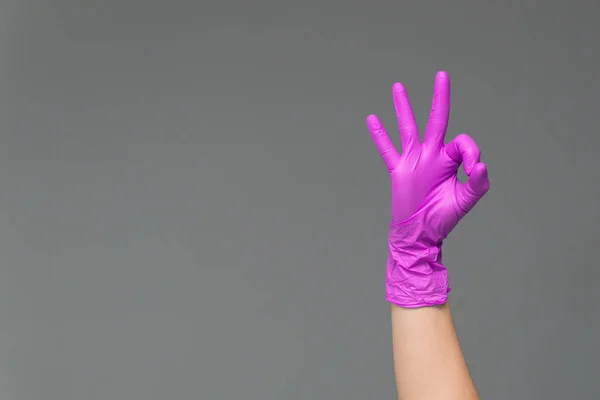 Рука Розовой Силиконовой Перчатке Сером Фоне Показывает Знак — стоковое фото