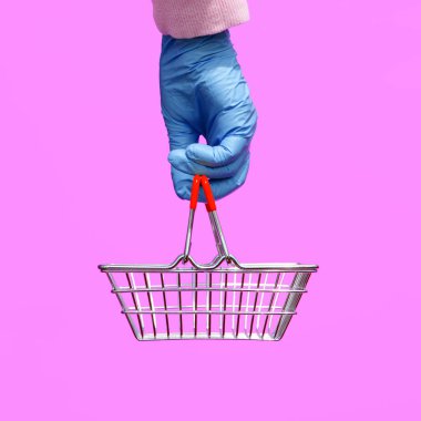 Tek kullanımlık parlak eldiven giymiş bir kadının elinde leylak arkaplanlı bir süpermarketten alınmış metal bir sepet bulunur. Koronavirüs salgını sırasında müşterilerin güvenliği. Pop sanat tarzı.