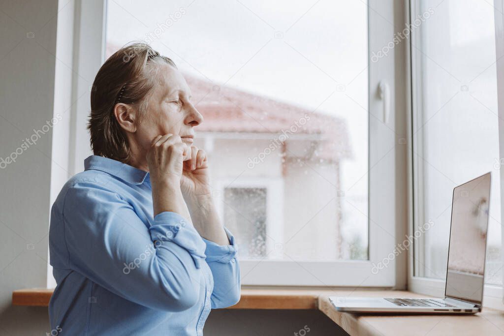 Prevention of aging. An adult woman is engaged in strengthening facial muscles on-line lessons at home during the quarantine in connection with the coronavirus epidemic.