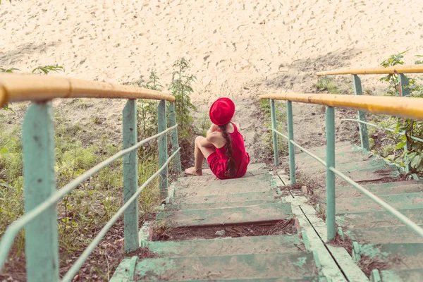 girl in red sits on the stairs