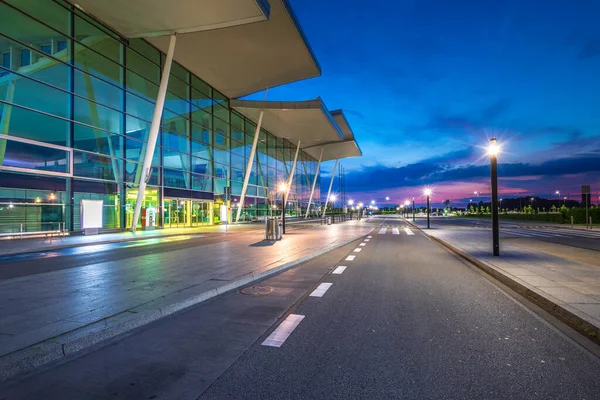 Wroclaw, Polonya 'daki modern havaalanı terminali. Boş cadde ve binanın önünde trafik yok. Cam duvarda gökyüzü yansımaları var. Gidiş ve gidiş girişlerini görüntüle