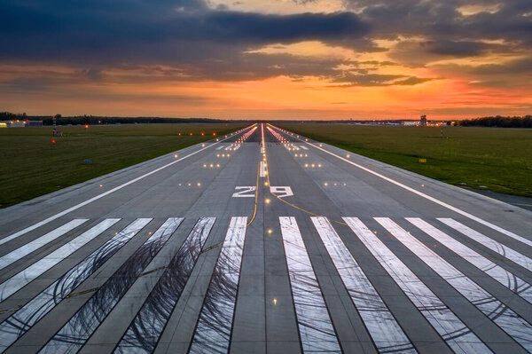 Empty airport runaway with braking and maneuvering marks, designation 29 and all navigation lights on at the colorful sunset, clear for airplane landing or taking off in Wroclaw  airport