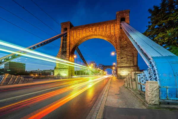 Wroclaw en ünlü Grunwaldzki asma köprüsü alacakaranlıkta hızlı hareket eden arabalarla, tramvaylar trafik ışığı yolları yaratıyor. Sokak tarafından görülen en bilinen şehir simgesi. 