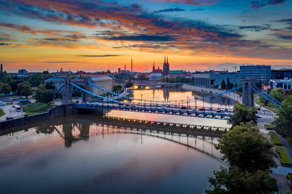 Drone view on the Grunwaldzki Bridge above Oder river in Wrocaw at beautiful sunset. Rushing traffic, illuminated historic buildings and bridges. Beautiful sky, light reflections on the blurry water