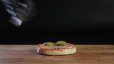 Bir büyük pirzola, peyniri, salatalık, domates, soğan, lahana, sos ve susam tohumu siyah bir arka plan ile topuz ile sulu hamburger