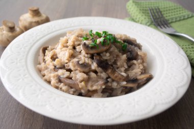 Klasik İtalyan vejetaryen mantarlı risotto arborio pilavı, mantar, soğan ve sarımsaklı fesleğen kurdeleli yeşil peçeteli ve çatallı.