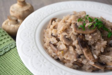 Klasik İtalyan vejetaryen mantarlı risotto arborio pilavı, mantar, soğan ve sarımsaklı fesleğen kurdeleli yeşil peçeteli ve çatallı.