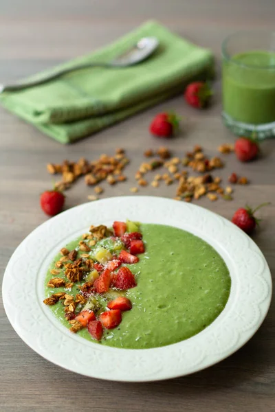 Green smoothie bowl garnished with homemade oat, nut and seed granola, coconut flakes, chia seeds, kiwi and strawberry — Stock Image Green Smoothie Bowl Garnished Homemade Oat Nut Seed Granola Coconut Stock Photo