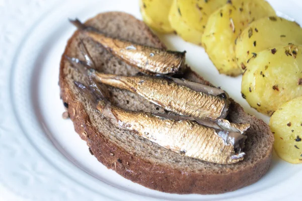 Canned sprats on rye bread served with herb baked potatoes — Stock Image Canned Sprats Rye Bread Served Herb Baked Potatoes Stock Picture