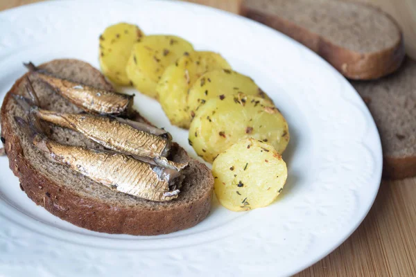 Canned sprats on rye bread served with herb baked potatoes — Stock Image Canned Sprats Rye Bread Served Herb Baked Potatoes Stock Picture