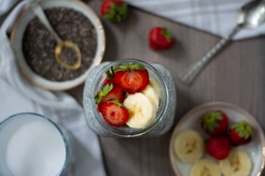 Sağlıklı vegan chia tohumu pudingi, üzerinde çilek ve muz olan bir kavanozda. Kırsal ve karanlık kavram