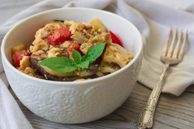 Taze domatesli ızgara patlıcan salatası, ceviz ve fesleğenle süslenmiş salata. Arka planda klasik çatal 