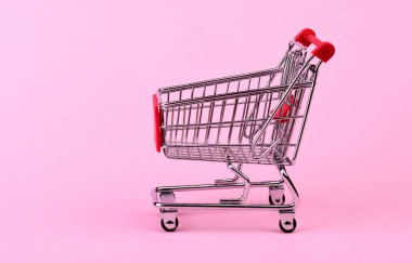 Pembe arka planda boş alışveriş arabası