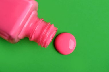 Yeşil arka plan üzerinde izole dökülmüş oje ile şişe