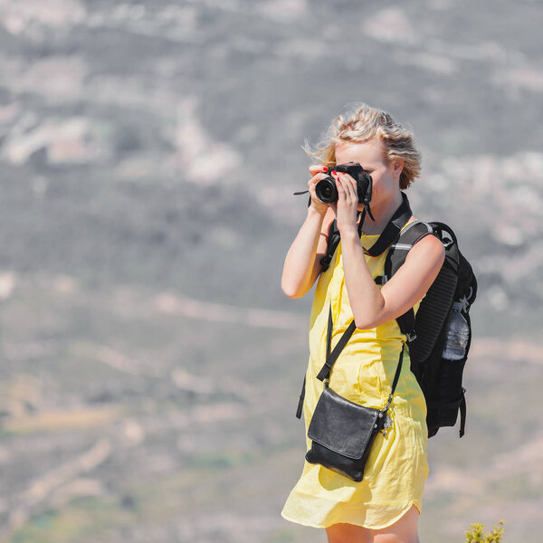 Female traveler with a backpack on her back enjoying the views from the mountains of Montserrat in Spain and makes a photo