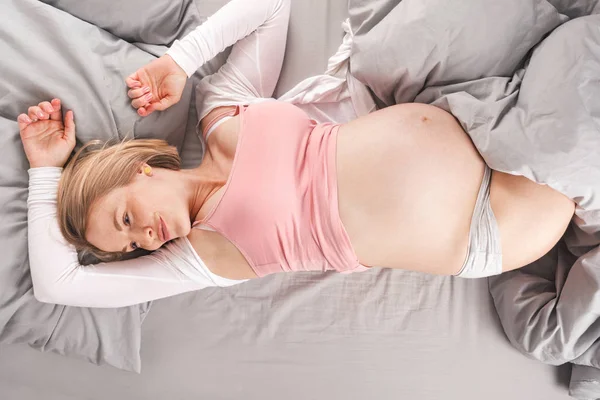 Giovane donna incinta felice si trova a letto e sogni del suo futuro figlio. Vista dall'alto — Foto Stock