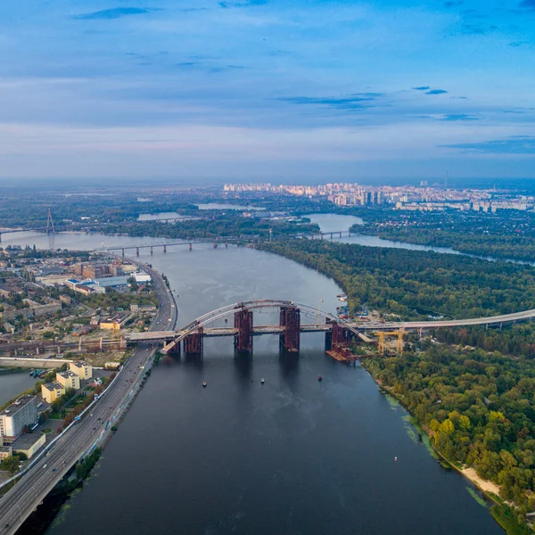 Panoramik manzaralı bir nehir, bitmemiş Köprüsü ve Şehir Parkı parçası ile modern bir şehir