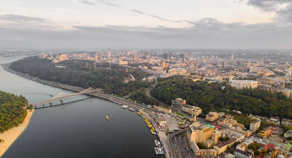 Panoramik Podol ilçe, şehir merkezi ve Vladimirskaya Gorka. Kiev Dinyeper Nehri, bir yaya köprüsü ve gün batımında geniş park alanı ile değil bankanın genel görünümü. — Stok fotoğraf