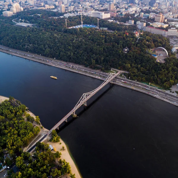 Vista panoramica del centro della città di Kiev. Veduta aerea della riva destra di Kiev con il fiume Dnieper, un ponte pedonale e una grande area parco al tramonto . — Foto Stock