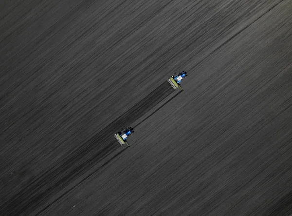 2 つの明るい青いトラクター黒に対して地面を耕して地球背景です。トップ ビュー — ストック写真