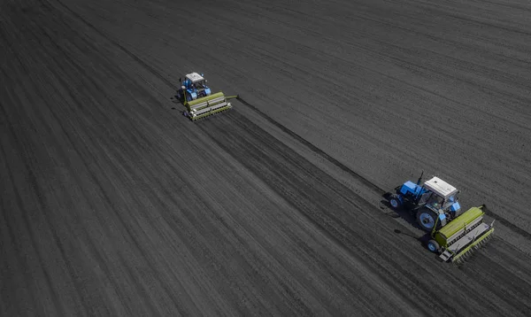 İki parlak mavi traktör kara toprağı çerçevede bir yere çiftçilik. — Stok fotoğraf