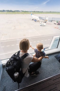Anne ve oğlu havaalanında uçak, pencere terminal bakarak yatılı.