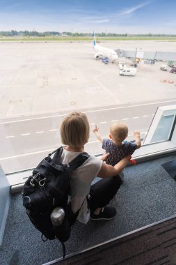 Anne ve oğlu havaalanında uçak, pencere terminal bakarak yatılı.