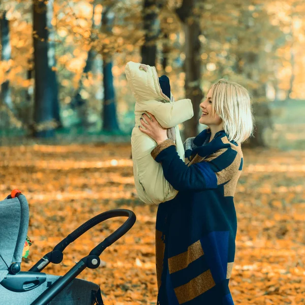 Une jeune mère avec une poussette parle sur son téléphone portable en marchant dans le parc — Photo
