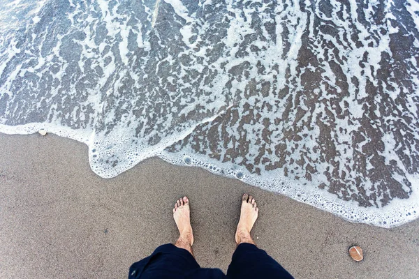 Blauwe golven in het zand met mannelijke voeten — Stockfoto