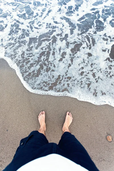 Olas azules en la arena con los pies masculinos —  Fotos de Stock