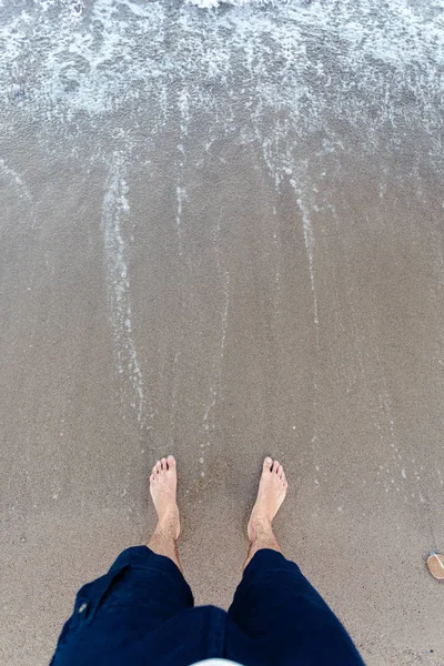 Olas azules en la arena con los pies masculinos — Foto de Stock