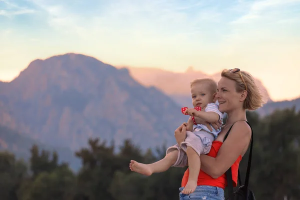 Jeune mère tenant son petit fils dans ses bras sur fond de paysage de montagne — Photo