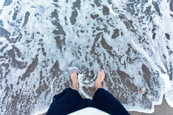 Olas azules en la arena con los pies masculinos —  Fotos de Stock