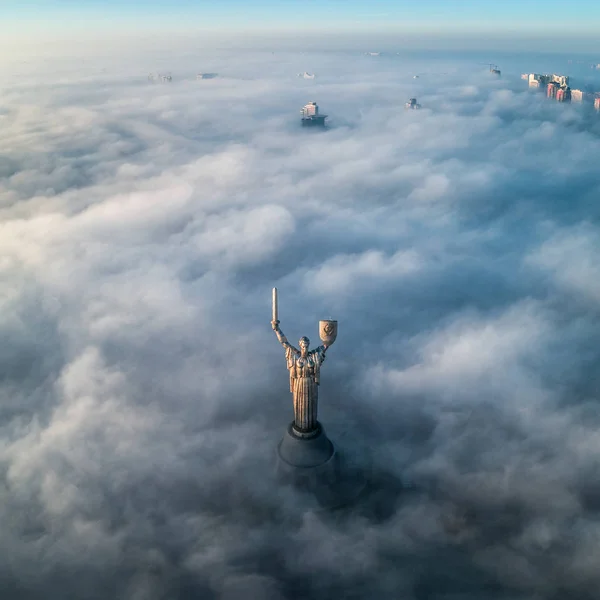 A cidade é coberta com nevoeiro espesso e saliente dele onde nem onde edifícios de edifício alto e o monumento Pátria — Fotografia de Stock