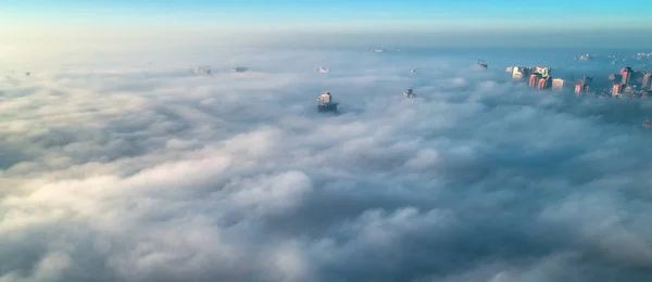 The city is covered with thick fog and protruding from it where neither where high-rise buildings — Stock Photo, Image