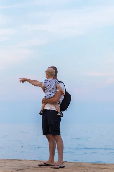 Papa tient son fils dans ses bras et montre la mer — Photo