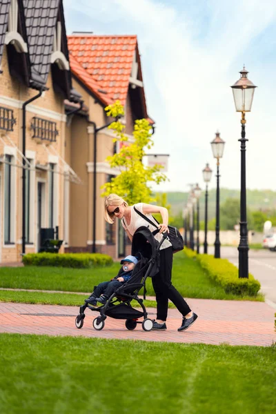 母は散歩にベビーカーで彼女の子供を運ぶ. — ストック写真