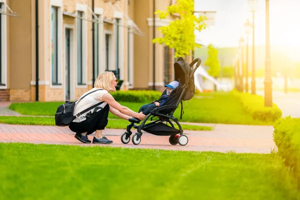 母は散歩にベビーカーで彼女の子供を運ぶ. — ストック写真