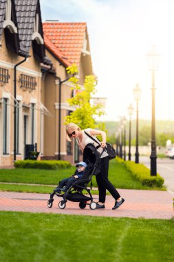 Anne çocuğunu bir yürüyüş için bir bebek arabası taşır.